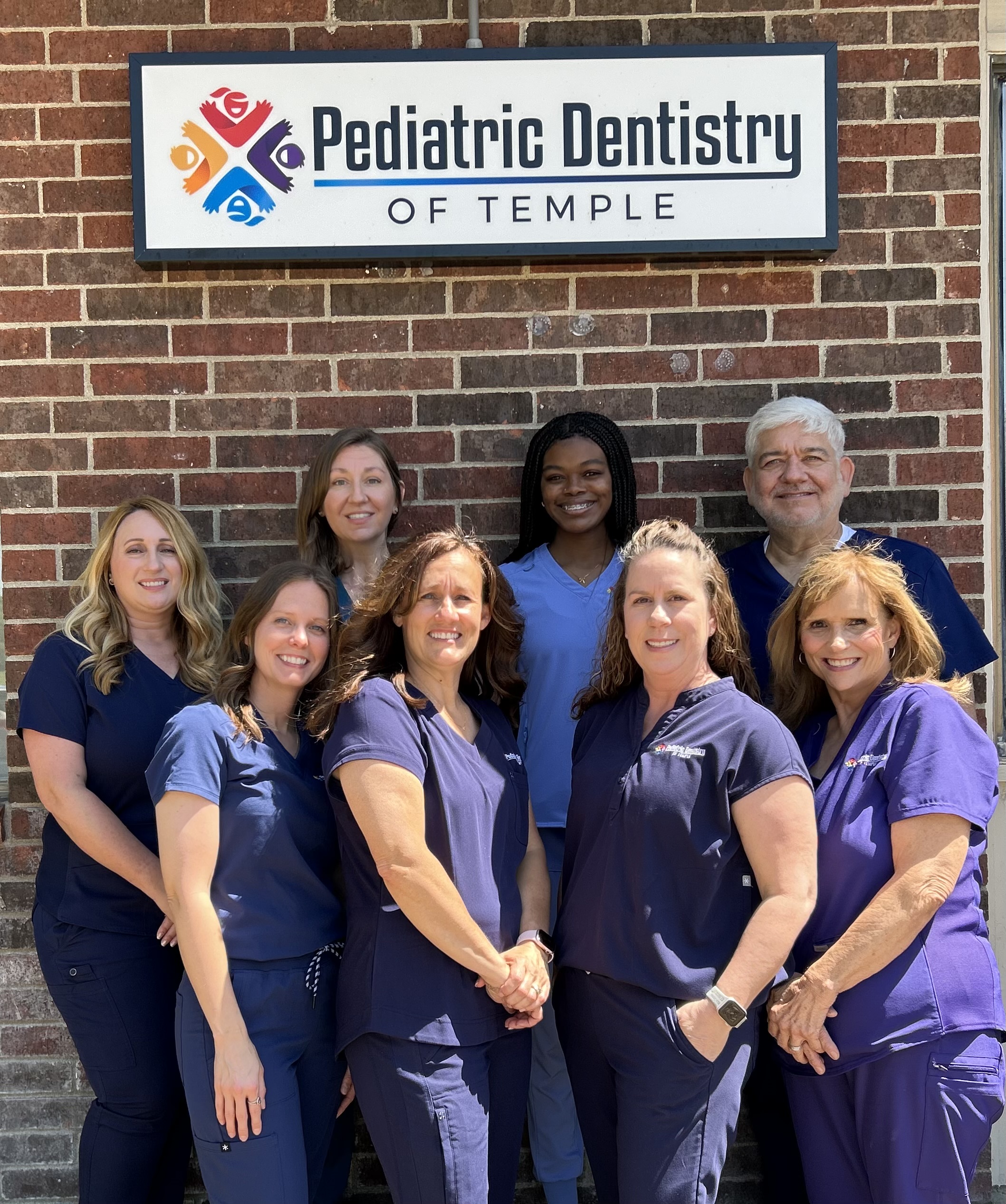 Dr. C. Brent Boyd and the full team at Pediatric Dentistry of Temple standing in front of the practice sign in Temple, Texas